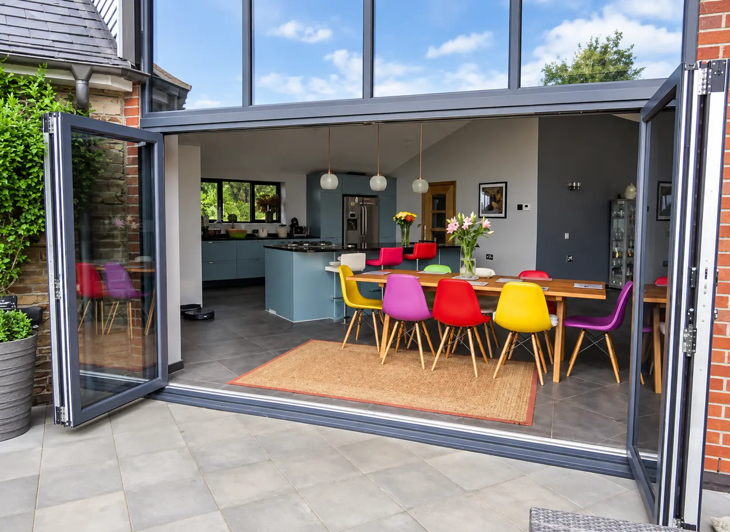 Dark-grey aluminium bifold doors fully open to a patio
